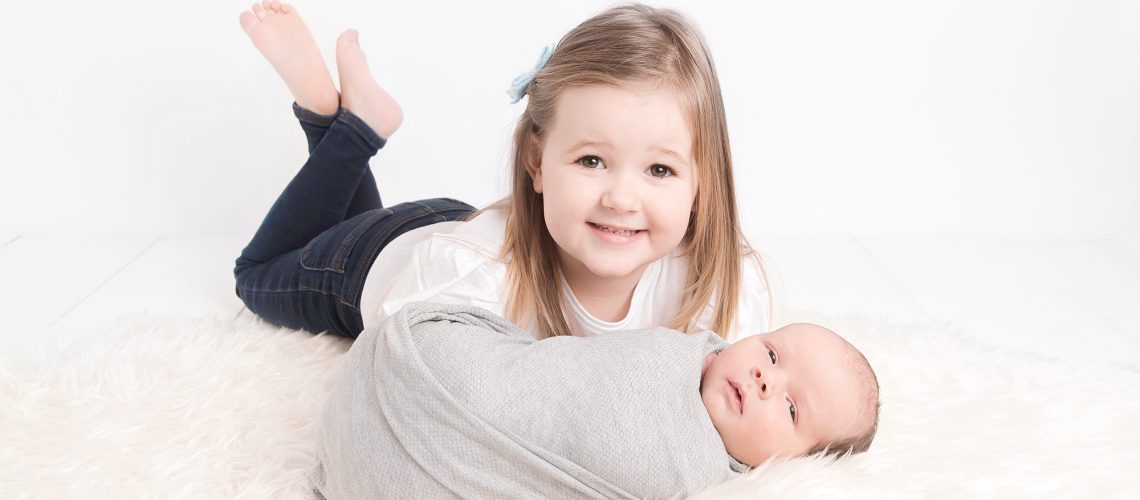 toddler girl and newborn posing, sibling and a new baby