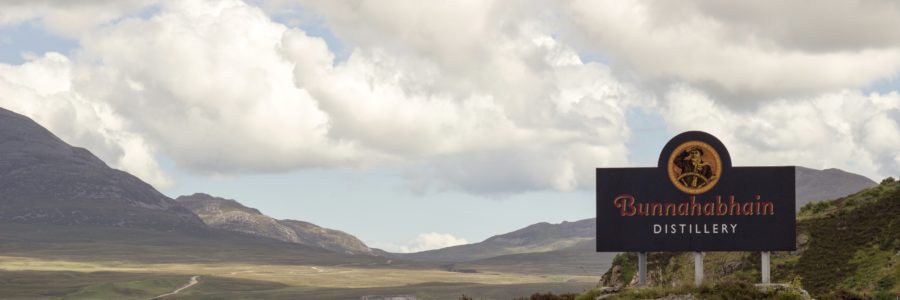 Ausblick auf Berg mit dem Schild der Bunnahabhain Destillerie im Vordergrund
