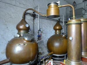 Die beiden Brennblasen von Strathearn: Unten eine große Kugel, auf der ein kurzer Zylinder und darauf eine Zwiebelform sitzt. Von der Spitze der Zwiebel führt der geschwungene Lyne-Arm das Destillat in einen Kondensator.