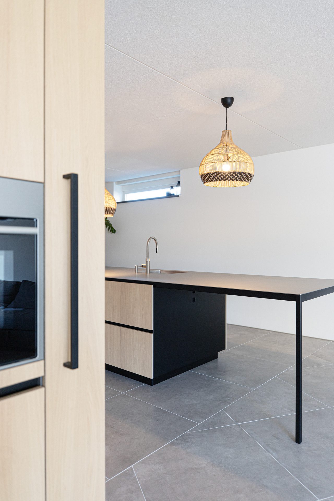 maatwerk-keuken-eiken-fineer-rvs-werkblad-kookeiland-zitgedeelte Keuken op maat in eikenfineer met kookeiland, massief RVS werkblad en zitgedeelte in Amsterdam