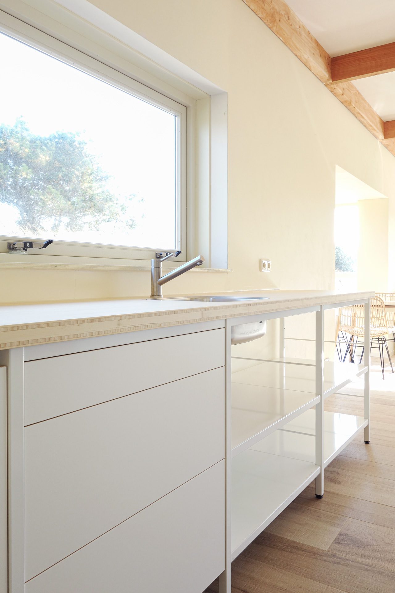 stalen-frame-keuken-wit-bamboe-werkblad Overzicht van het witte stalen frame keukenblok met bamboe werkblad en spoelbak bij het raam