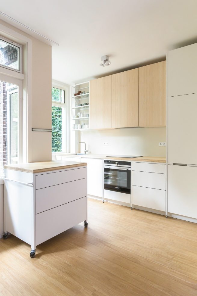 Keuken op maat met stalen frame, bamboe werkblad, witte HPL fronten en verrijdbare keukentrolley in Amsterdam