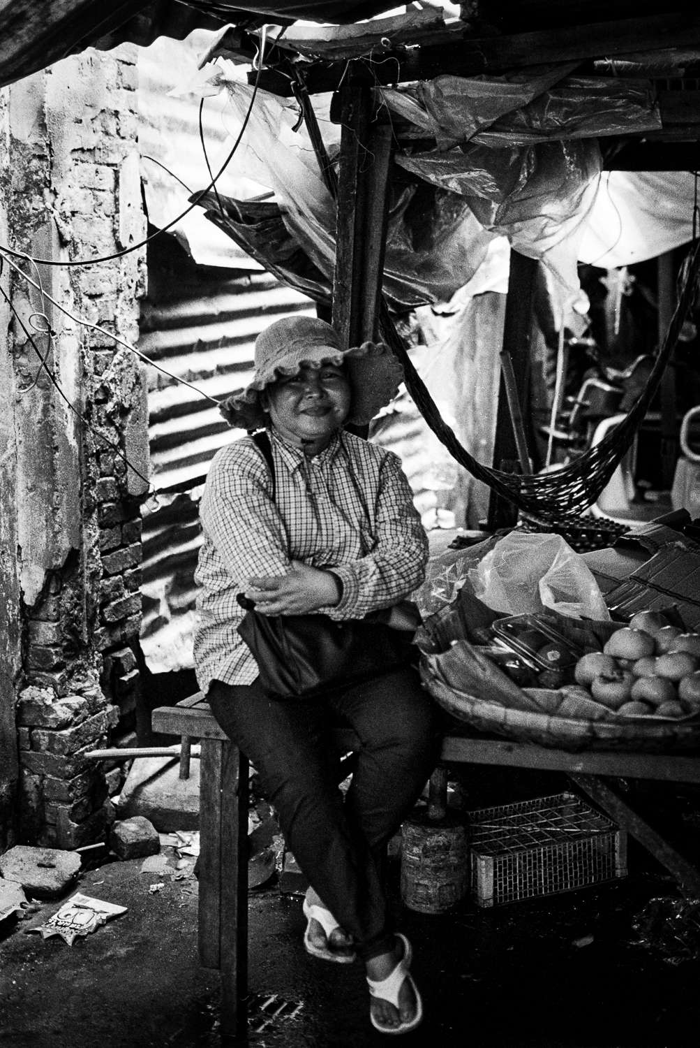 foods and snack seller taking a break in a dark and cool alley of Phnom Penh