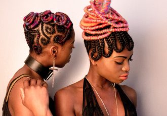 black and white photo of two black models in colorful intricate braids and vintage fashion