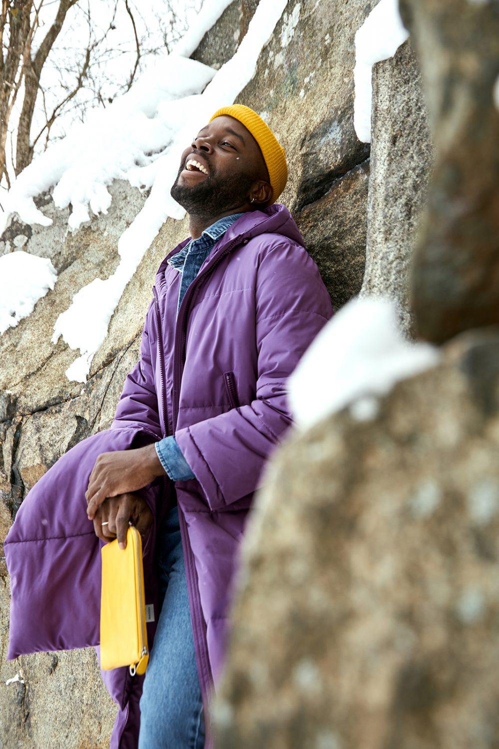 laughing male model in purple puffer coat with yellow hat