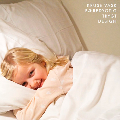 Smilende pige putter med sengetøj fra Kruse Vask