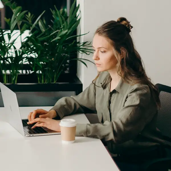 medarbetare-på-kontor Kvinna som arbetar med mugg och dator