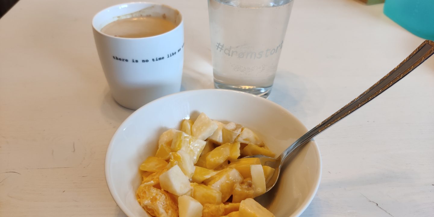 Fruktsalat i skål, kaffe og vannglass