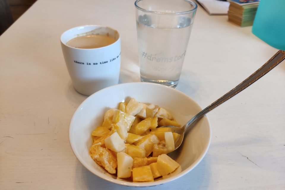 Fruktsalat i skål, kaffe og vannglass