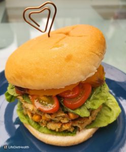 assembled veggie burger on a blue plate. Burger held together with heart topped metal spike.