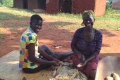 2022-01-Linet und Melvine auf dem Boden sitzend Mais schälend