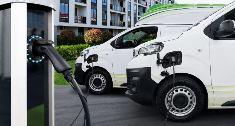 Electric,Vehicles,Charging,Station,On,A,Background,Of,Delivery,Vans.