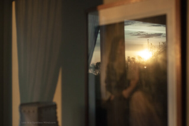 A moody photo of an early sun reflected in the glass of a picture frame.