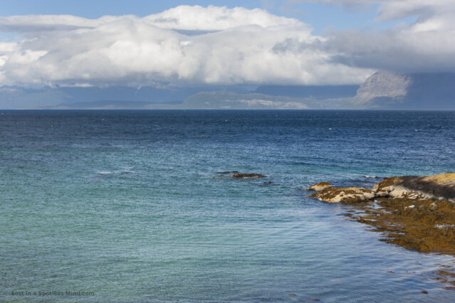 An incredibly blue sea, under a cloudy sky.