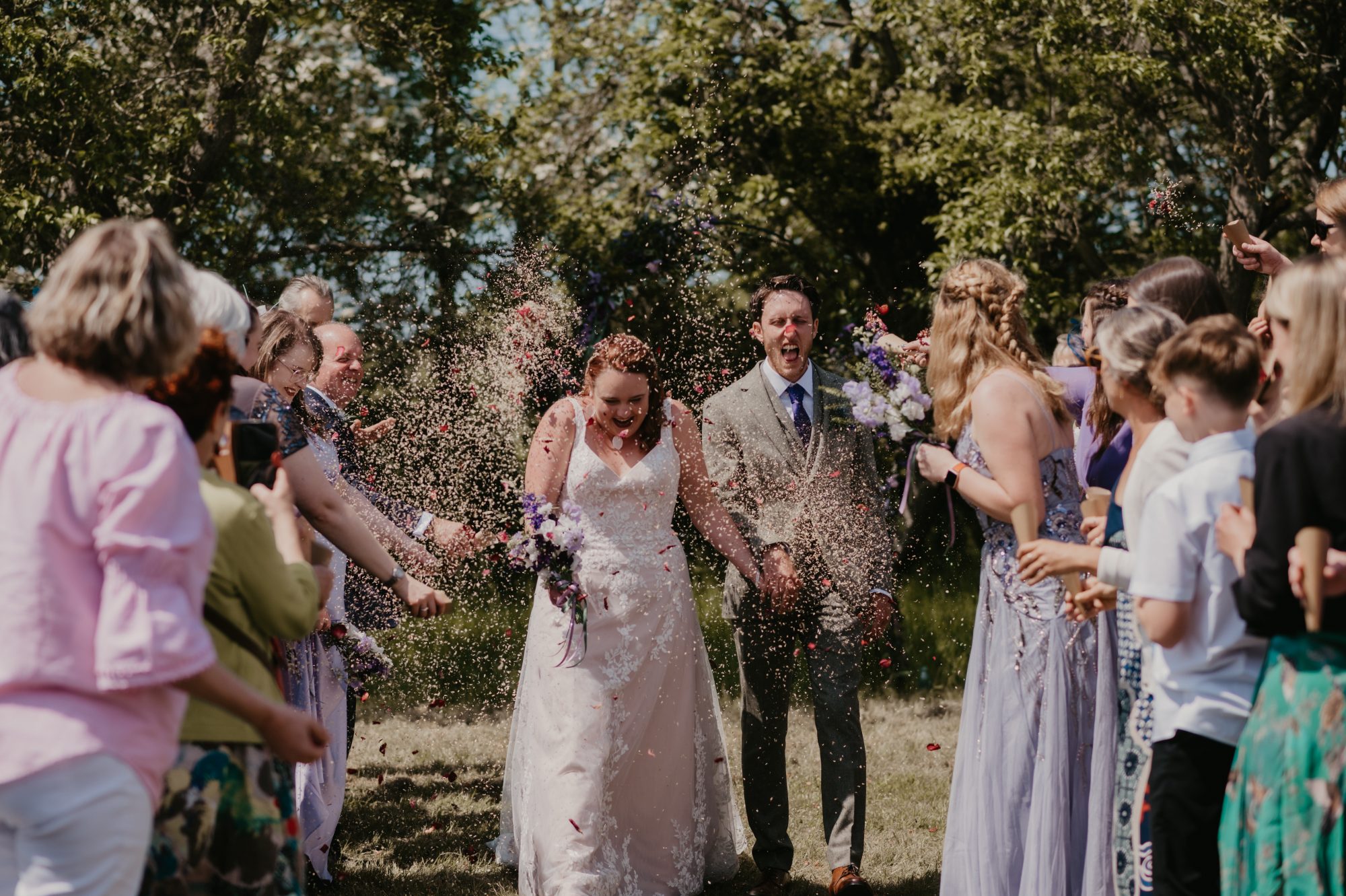 A bride and groom walking amongst confetti