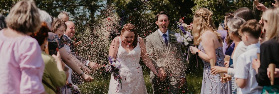 A bride and groom walking amongst confetti