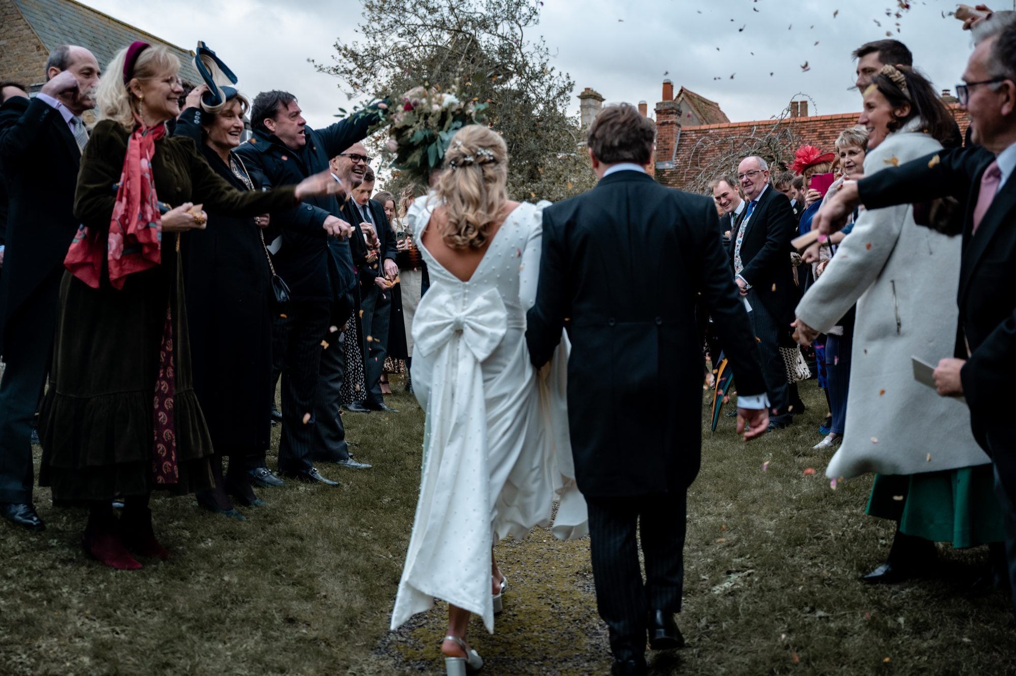 A bride and groom walking away through confetti