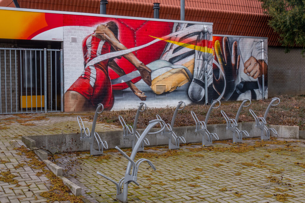 Een muurschildering tegen ongewenste graffiti om te voorkomen dat de buitenmuren van de sporthal keer op keer worden beklad met ongewenste illegale tags en graffiti. Ook heeft GOMAD Graffix hier een anti-graffiti coating over de muurschildering gezet ter bescherming tegen eventuele toekomstige bekladdingen.