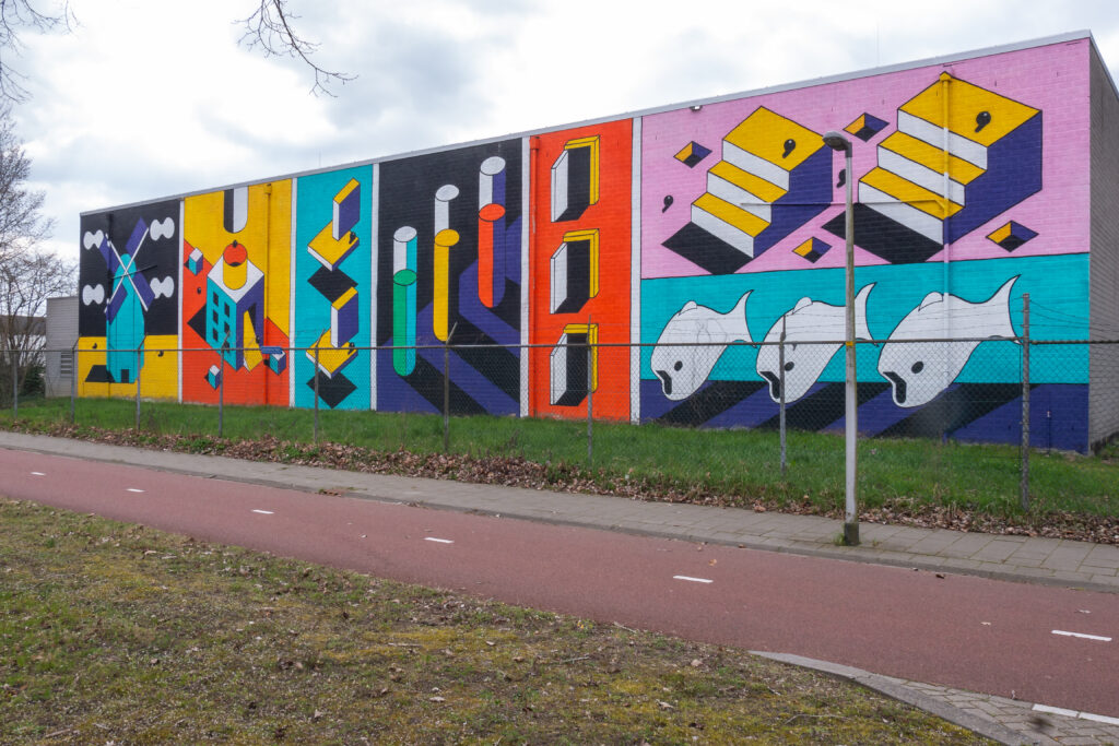 een mural op het S/Park terrein gemaakt door Johan Moorman. Dit is het voormalige AkzoNobel-terrein in Deventer en een plek met een veelbewogen geschiedenis. Molens, groei, brand, ondernemersgeest, de drie haringen, fusies, krimp, oorlog, slachtoffers: alles passeerde de afgelopen 180 jaar de revue. Nog altijd is dit een plek vol energie, een broedplaats voor nieuwe ideeën, nu onder de naam S/park. Juist daarom past deze Street Art Streets mural zó goed op deze plek.