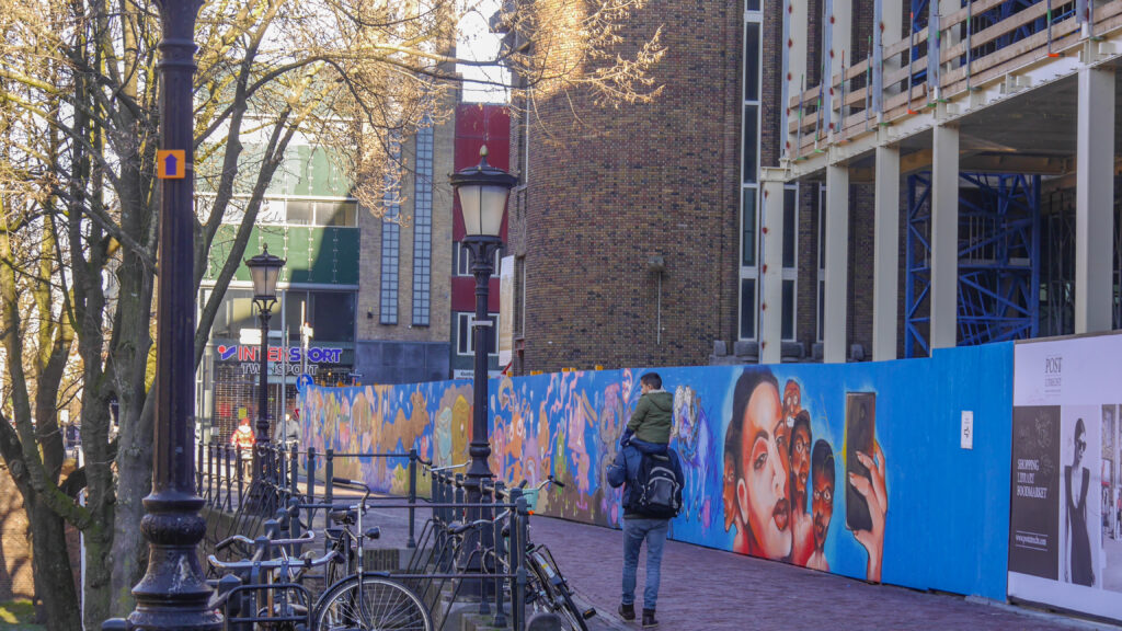 Rondom het voormalige postkantoor op de Neude stonden meterslange houten bouwschuttingen die onder de illegale posters en graffiti zaten. Niet echt een visitekaartje in de binnenstad van Utrecht.
Greetings from Utrecht heeft samen met 15 graffitikunstenaars deze schuttingen opgepimpt met bijzondere kunstwerken. Vele bezoekers, bewoners, de eigenaar van het pand ASR vastgoed en vooral ook de omliggende ondernemers hebben maandenlang kunnen genieten van de fleurige muren