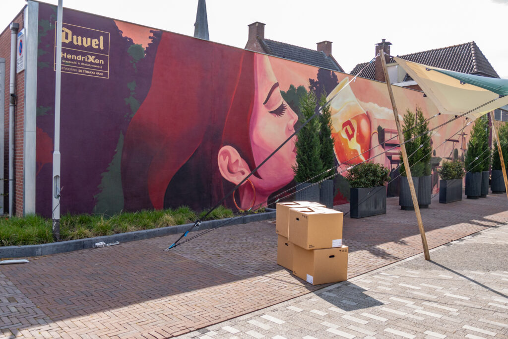 De letter ‘D’ in de muurschildering de eerste letter van de Belgische bierbrouwer Duvel Moortgat en tegelijkertijd een stiekeme knipoog naar de stad Doetinchem? 
Het horecaplein aan de Grutstraat is een initiatief van de familie Hendrixen, van de gelijknamige stadsbrouwerij schuin tegenover.