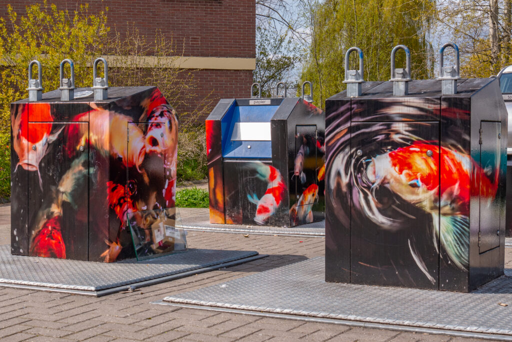 In close up zie je de koikarpers zwemmen. Het lijkt wel alsof je naar een aquarium kijkt. Met het opvallende beeld willen ze voorkomen dat bewoners hun afval dumpen naast de containers.