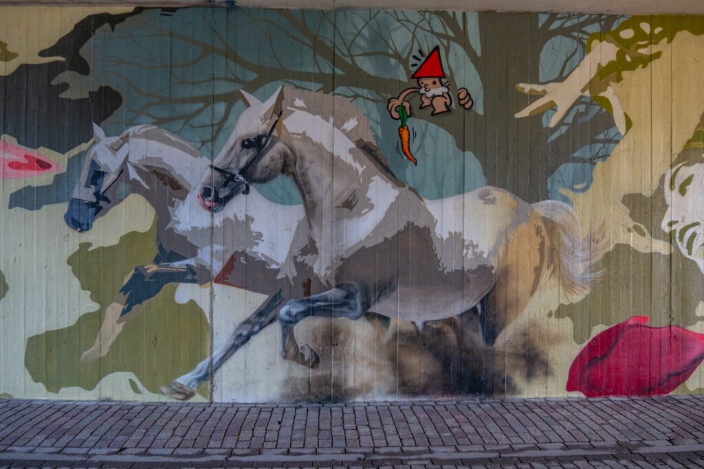 De boog maakt de verbinding van Den Haag Centraal naar Leiden Centraal en Schiphol mogelijk. Er kwam vanuit het stadsdeel en de buurtbewoners de vraag of er iets met Street Art in de Schipholboog gemaakt kon worden. 
En als kleine verrassing is de Kabouter uit Utrecht ook nog stiekem om de hoek komen kijken.