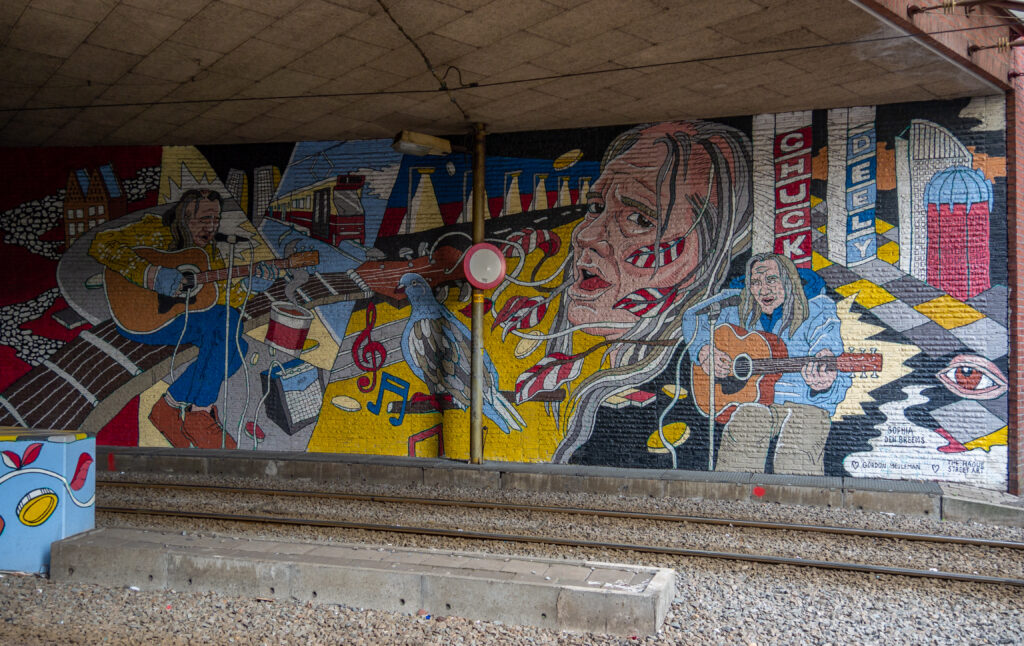 Haags Icoon: Chuck Deely Hij was een Amerikaans zanger die in de Haagse binnenstad zijn muziek ten gehore bracht. Hij had een vergunning voor het leven in Den Haag als straatmuzikant. Aan het einde van de tramtunnel speelde hij vaak. Ze wilde Chuck "zo mooi en kleurrijk mogelijk" laten zien, net als zijn muziek.