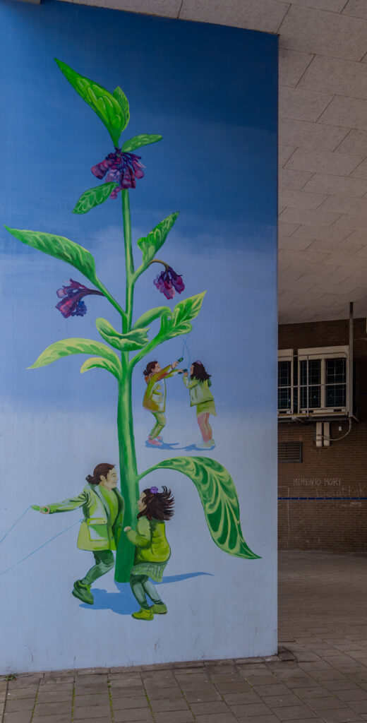 Het wooncomplex De Ellips is een ellipsvormig wooncomplex met een grote binnentuin. De entree poort naar de tuin is maar liefst tweeënhalve verdieping hoog en acht appartementen breed. Drie enorme betonnen platen ondersteunen de entree. Zes vrolijke afbeeldingen van ieder 5 meter hoog en 2.20 meter breed.