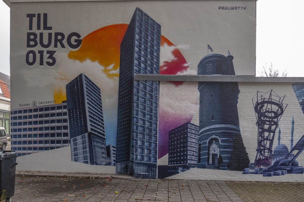 De muur toont de skyline van Tilburg. Er staan verschillende taferelen zoals het reuzenrad van de kermis, de Beka fabriek, het Willem II stadion en de uitkijktoren in het Spoorpark