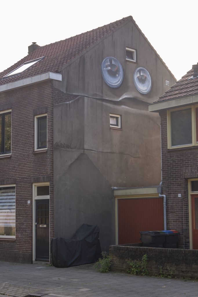 Lachende huis.  Het werk is vaak een spel van wat er al op de muur te zien is en daarmee een grap uithalen. Zo is de muur van dit huis wel een heel leuk gezicht. Het werk moet vooral inspireren.