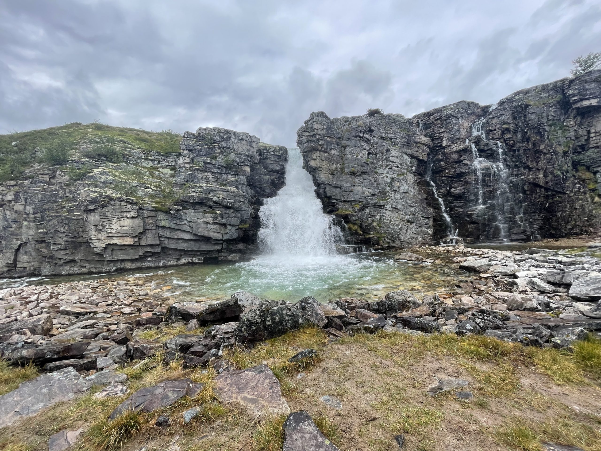 Huge waterfall cascading inbetween two steep grey cliffs