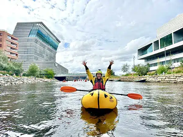 Girl throwing her hands up happy while packrafting on the Akerselva River in Oslo