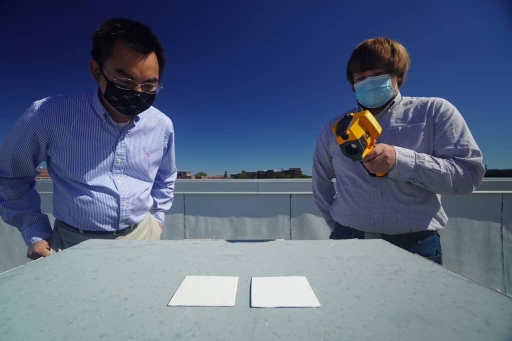 Purdue researchers Xiulin Ruan and Joseph Peoples use an infrared camera to compare the cooling performance of white paint samples on a rooftop. Credit: Purdue University photo/Jared Pike. Whitest white