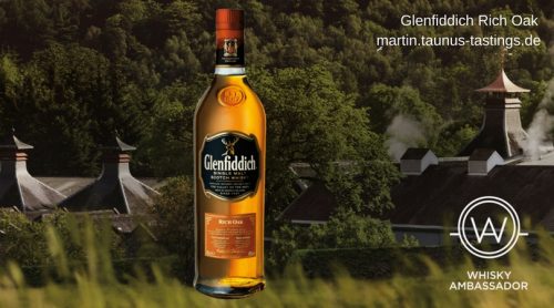 Eine Flasche Glenfiddich Rich Oak, im Hintergrund die Brennerei