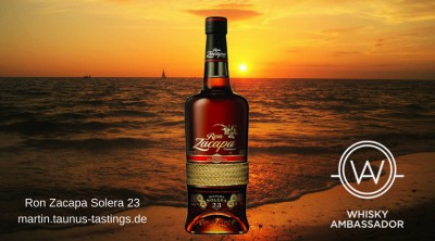 Eine Flasche Ron Zacapa Solera 23, im Hintergrund ein Sonnenuntergang über dem Meer