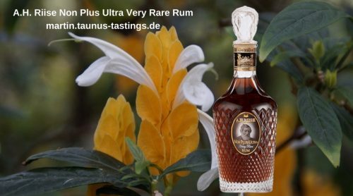 Eine Flasche A.H. Riise non plus Ultra Rum, im Hintergrund eine Blüte