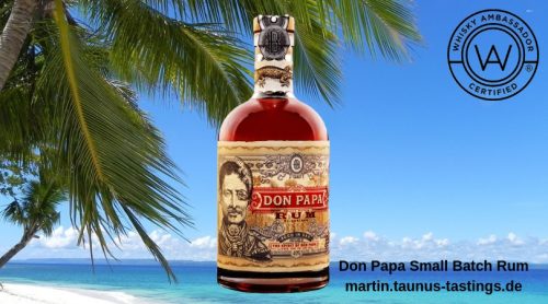 Eine Flasche Don Papa Small Batch Rum, im Hintergrund ein Starnd in der Karibik