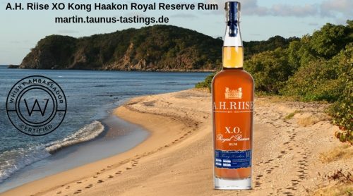 Eine Flasche A.H.-Riise-XO-Kong-Haakon-Royal-Reserve-Rum, im Hintergrund ein Strand in der Karibik