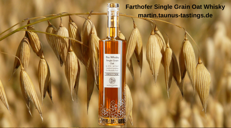 Eine Flasche Farthofer Single Grain Oat Whisky, im Hintergrund ein Haferfeld