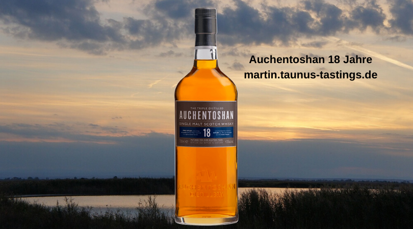 Eine Flasche Auchentoshan 18 Jahre, im Hintergrund ein Sonnenuntergang in den schottischen Lowlands
