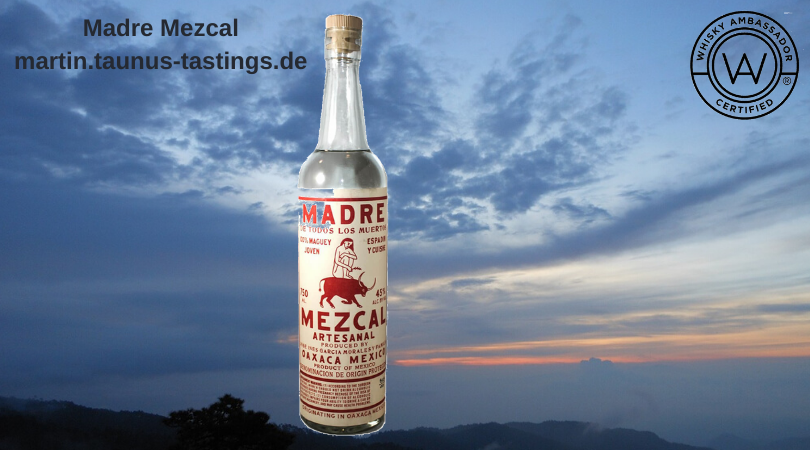 Eine Flasche Madre Mezcal mit dem Himmel von Oaxcaca im Hintergrund