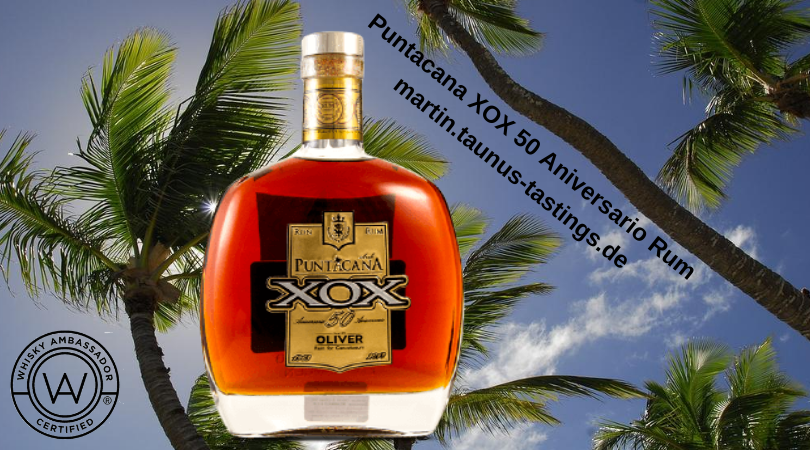 Eine Flasche Puntacana XOX 50 Aniversario Rum mi einem Strand und Palmen im Hintergrund