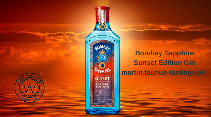 Eine Flasche Bombay Sapphire Sunset Edition Gin, im Hinergrund ein Sonnenuntergang am Meer