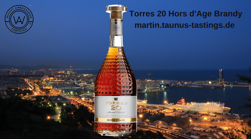 Eine Flasche Torres 20 Hors d'Age Brandy, im Hintergrund der Hafen von Barcelona