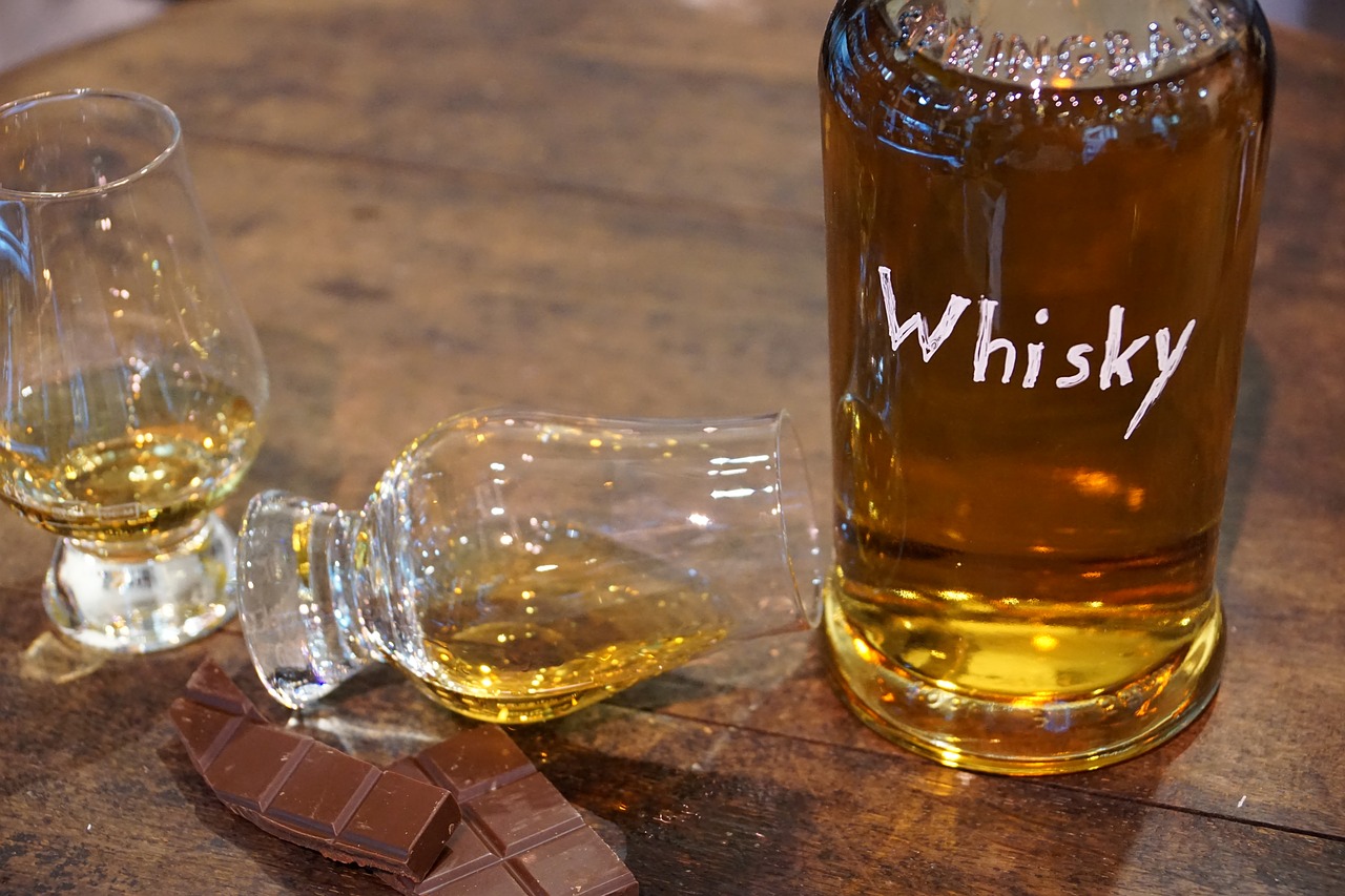 Eine Flasche mit Whisky oder Whiskey mit zwei Glencairn-Gläßern und Schokolade