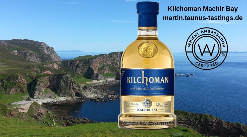 Eine Flasche Kilchoman Machir Bay, im Hintergrund eine Bucht auf der Insel Islay in Schottland