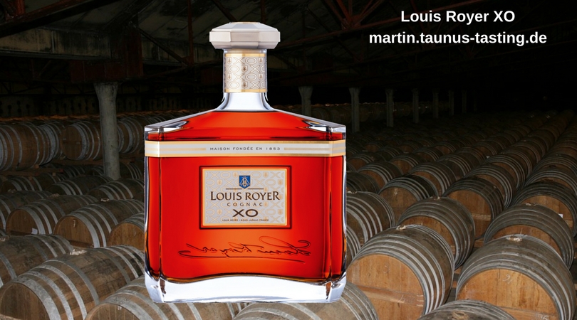 Eine Flasche Louis Royer XO Cognac, im Hintergrund ein Fasslager