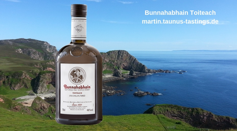 Eine Flasche Bunnahabhain Toiteach, im Hintergrund die Küste von Islay