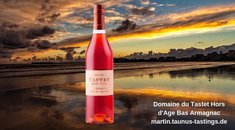 Eine Flasche Domaine du Tastet Hors d'Age Bas Armagnac, im Hintergrund die Küste in Frankreich